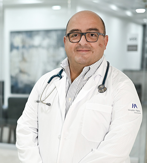 Es la foto de perfil de un pediatra neonatólogo en Ciudad de México de Hospital Angeles. El doctor es de tez apiñonada, viste un un uniforme negro y tiene las letras de su nombre bordadas en color blanco. 