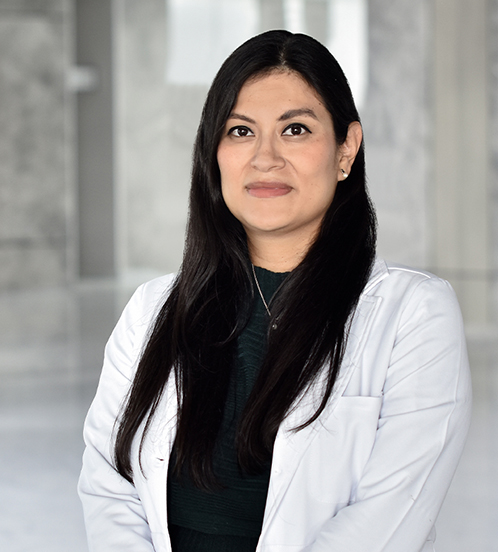 Es la foto de perfil de un neonatólogo en Querétaro de Hospital Angeles Centro Sur. Usa una bata con una playera negra, su cabello es largo y oscuro. Es de tez morena y usa joyería dorada.