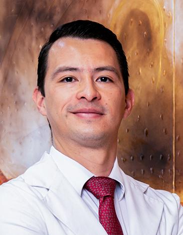 Es la foto de perfil de un ortopedista y traumatólogo en León de Hospital Angeles León. Utiliza una bata blanca con camisa y corbata. está sonriendo suavemente.