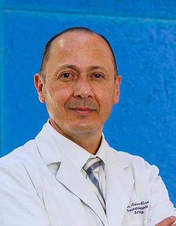 Es la foto de perfil de un ortopedista y traumatólogo en León de Hospital Angeles León. Tiene una bata blanca, camisa blanca y corbata. Tiene los brazos cruzados.