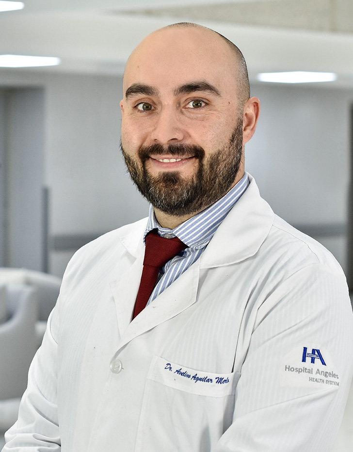 Es la foto de perfil de un ortopedista y traumatólogo en Ciudad de México de Hospital Angeles.Usa una camisa azul claro con rayas blancas y una corbata; también tiene puesta una bata blanca. Es calvo y tiene una barba café.