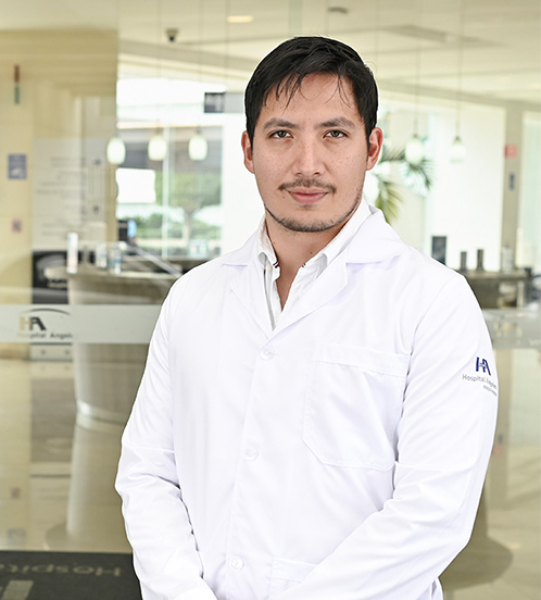 Es la foto de perfil de un cirujano general en Ciudad de México de Hospital Angeles. Usa una bata y camisa blanca. Tiene el cabello lacio y castaño. Su bigote es café.