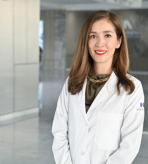 Es la foto de perfil de una ginecóloga y obstetra en Querétaro de Hospital Angeles Centro-sur. Usa una bata blanca con una blusa color verde olivo y un collar dorado. Tiene el cabello café, corto y lacio.