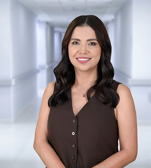 Es la foto de perfil de una pediatra en Ciudad Juárez de Hospital Angeles Ciudad Juárez. Viste una bata blanca, una blusa negra y tiene labial color rosa.