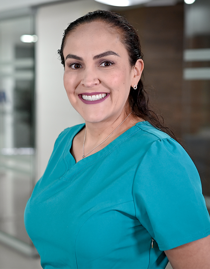 Es la foto de perfil de una ginecóloga, obstetra y especialista en biología de la reproducción en Ciudad de México de Hospital Angeles Santa Mónica. Usa un unforme médico color azul. Tiene el cabello peinado en media cola y está sonriendo.