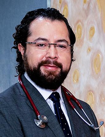 Es la foto de perfil de un oncólogo médico en León de Hospital Angeles León. Usa un saco oscuro, con camisa blanca, con una corbata oscura con lunares blancos.