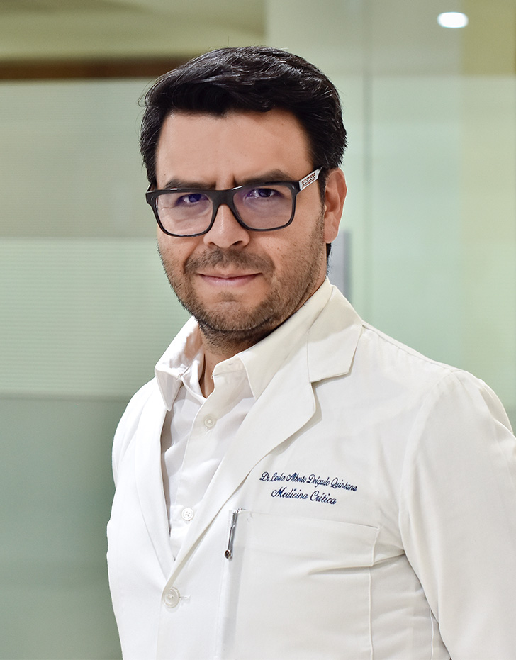 Es la foto de perfil de un intensivista e internista en Ciudad de México de Hospital Angeles Mocel. Usa una bata y camisa blanca con unos lentes de armazón negros y cuadrados. Tiene el cabello y barba café oscuro.