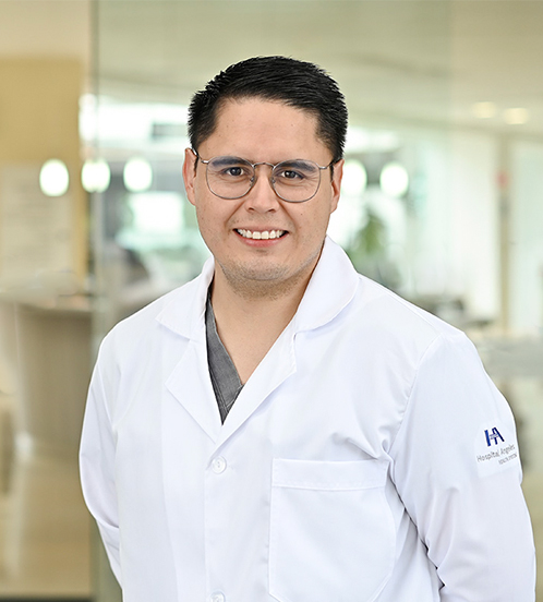 Es la foto de perfil de un geriatra y especialista en medicina del dolor y paliativa en Ciudad de México de Hospital Angeles Acoxpa. Usa una bata color blanco con un uniforme médico color gris. Tiene el cabello negro y usa lentes.