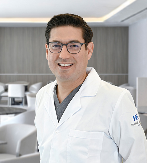 Es la foto de perfil de un ortopedista y traumatólogo, especialista en medicina del deporte y artiscopía en San Pedro Garza de Hospital Angeles Valle Oriente. Usa una bata blanca con una corbata gris. Tiene lentes y cabello negro.