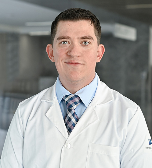 Es la foto de perfil de un ginecólogo y obstetra en Querétaro de Hospital Angeles Centro Sur. Usa un traje beige claro, una camisa azul claro y una corbata azul marino con lineas beige y blancas.