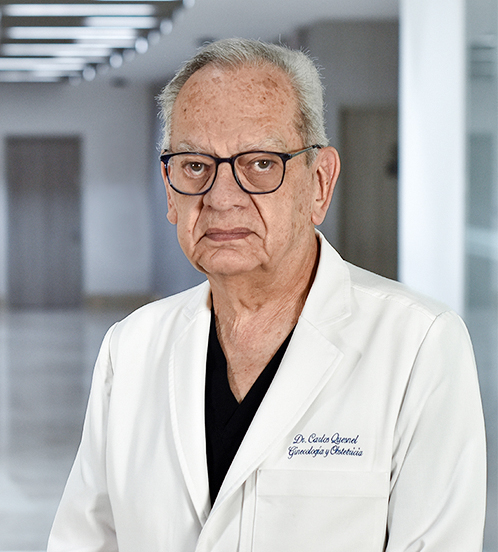 Es la foto de perfil de un ginecólogo y obstetra en Huixquilucan de Hospital Angeles Lomas. Usa una bata blanca con un uniforme negro, lentes cuadrados y cabello canoso.