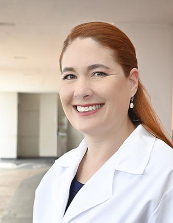 Es la foto de perfil de un nutriólogo en León de Hospital Angeles León. Utiliza una bata blanca con blusa negra, tiene el cabello pelirrojo y aretes blancos.