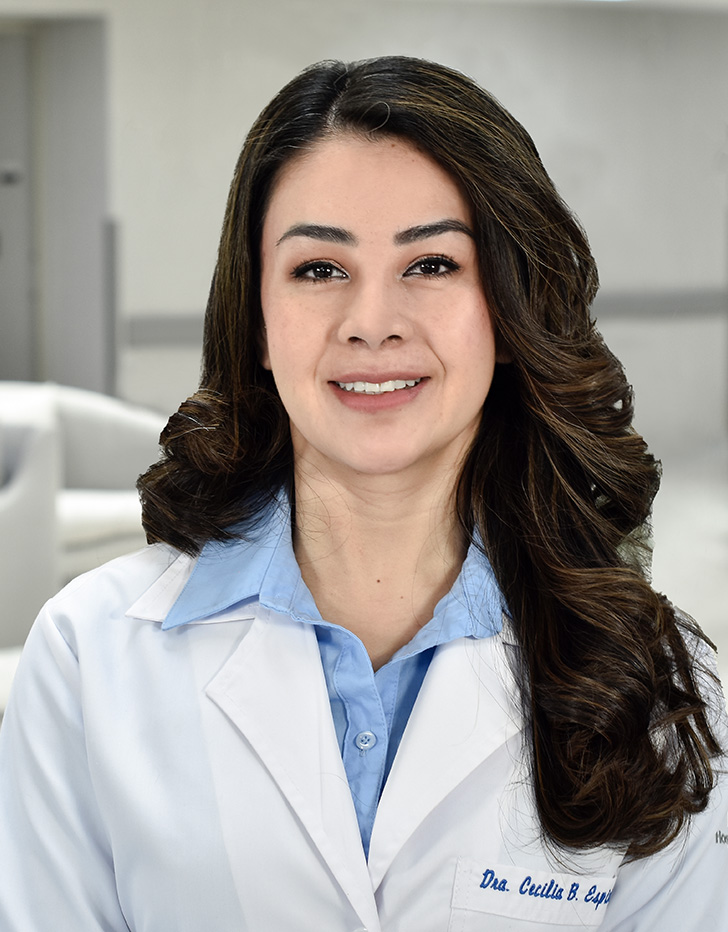 Es la foto de perfil de una otorrinolaringóloga en Ciudad de México de Hospital Angeles Metropolitano. Usa una bata blanca con una camisa color azul claro. Tiene el cabello café oscuro, corto y ondulado. Está sonriendo.