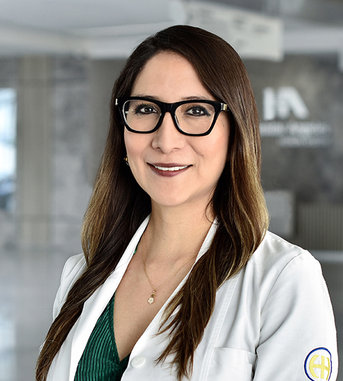 Es la foto de perfil de una neonatóloga en Querétaro de Hospital Angeles Centro Sur. Usa una bata blanca, blusa verde, lentes con marco negro y su cabello es lacio con luces rubias.