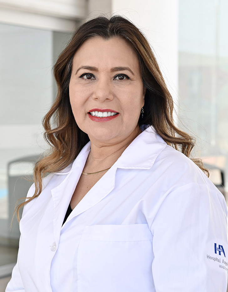 Es la foto de perfil de una pediatra en Tijuana de Hospital Angeles Tijuana. Usa un suéter negro con cuadros. Tiene el cabello largo, ondulado y café.