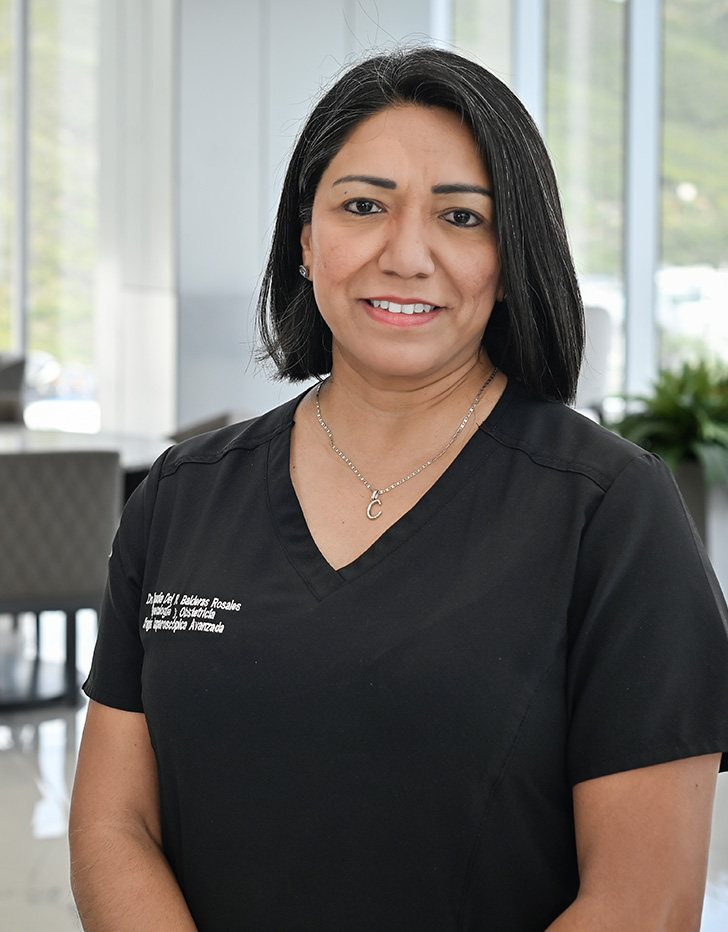 Es la foto de perfil de una bióloga de la reproducción y ginecóloga y obstetra en San Pedro Garza García de Hospital Angeles Valle Oriente. Usa un uniforme color negro con joyería color plata. Tiene el cabello corto color negro con algunas canas.