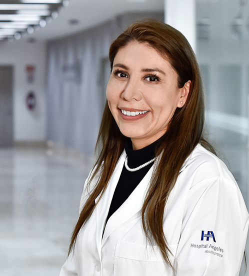 Es la foto de perfil de un pediatra en Huixquilucan de Hospital Angeles Lomas. Usa una bata blanca con un suéter negro con cuello alto, collar de perlas. Tiene cabello largo lacio y está sonriendo.