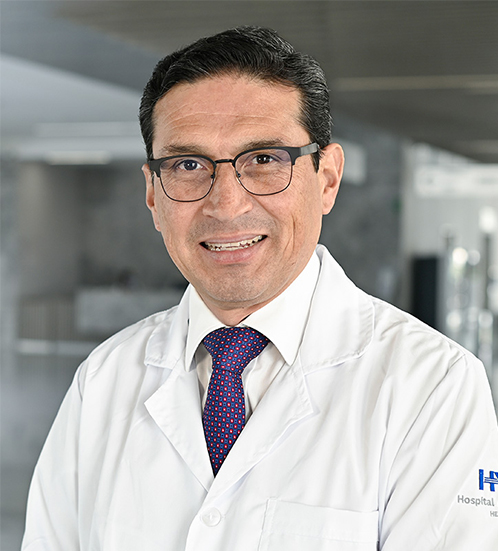 Es la foto de perfil de un ginecólogo y obstetra en Querétaro de Hospital Angeles Centro Sur. Usa una bata blanca, camisa blanca y corbata azul cielo brillante.