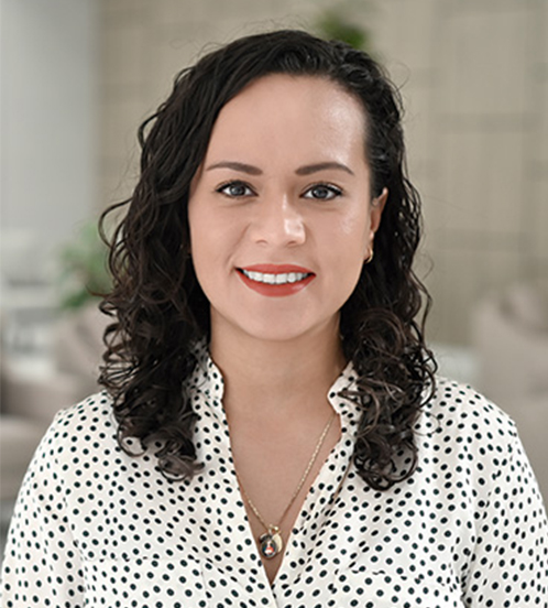 Es la foto de perfil de una ginecóloga y obstetra en Querétaro de Hospital Angeles Centro Sur. Usa una blusa blanca con lunares negros, un collar dorado, su cabello es mediano y ondulado.