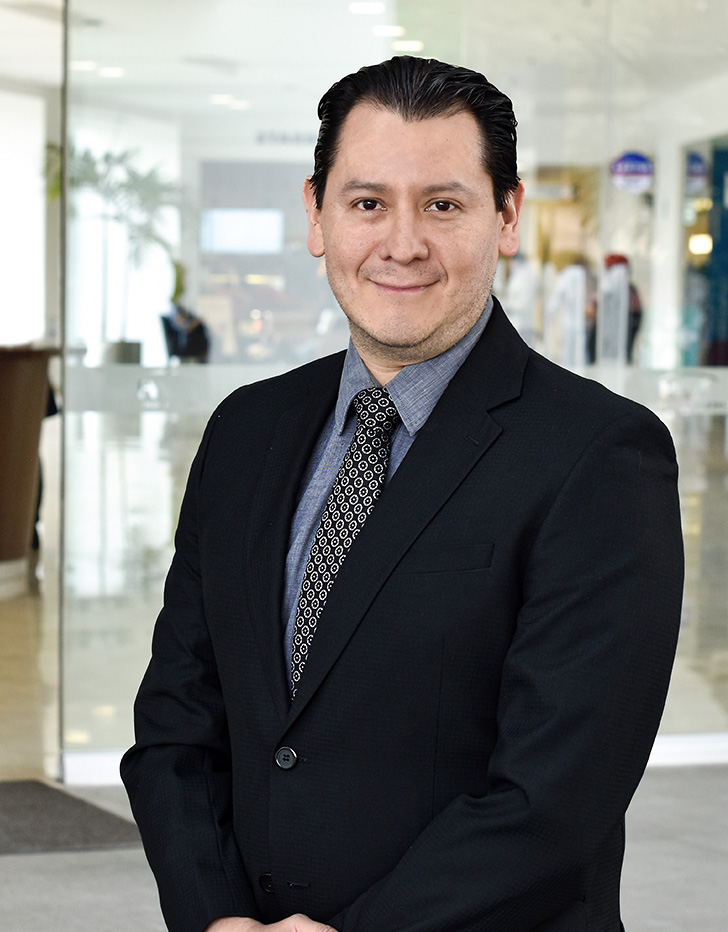 Es la foto de perfil de un inmunólogo y alergólogo en Ciudad de México de Hospital Angeles Acoxpa. Usa un traje  color negro con una camisa gris gris y una corbata negra con detalles grises. Tiene el cabello negro y los brazos cruzados enfrenrte.