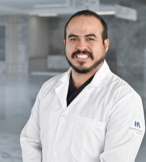 Es la foto de perfil de un cardiólogo en Querétaro de Hospital Angeles Centro-sur. Usa una bata de Hospital Angeles blanca con un uniforme médico color negro. Tiene poco cabello color café oscuro.