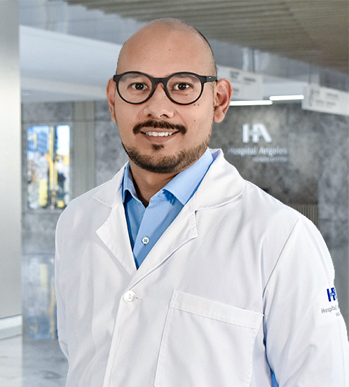 Es la foto de perfil de un médico en medicina crítica en Querétaro de Hospital Angeles Centro-sur. Tiene puesta una bata de Hospital Angeles con una camisa azul claro. Es calvo y tiene barba color café. Usa lentes.