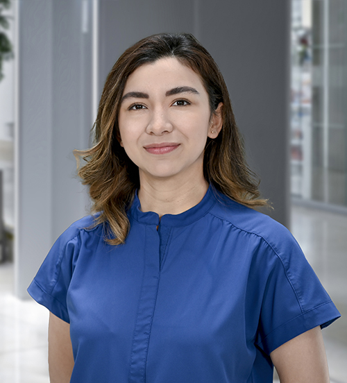 Es la foto de perfil de una cirujana general en Huixquilucan, Estado de México de Hospital Angeles Lomas. Usa un uniformr médico color azul. Tiene el cabello medio recogido y ondulado de color café. Esta sonriendo ligeramente.