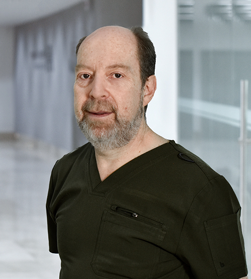Es la foto de perfil de un pediatra y neonatólogo en Huixquilucan de Hospital Angeles Lomas. Usa un uniforme negro con cuello V, barba canosa y está sonriendo. 