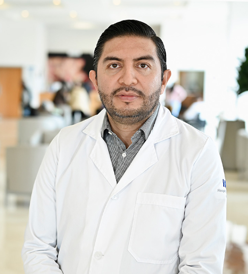 Es la foto de perfil de un médico internista en Xalapa de Hospital Angeles Xalapa. Usa una bata blanca y camisa azul. Tiene el cabello y barba negro.