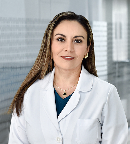 Es la foto de perfil de una ginecóloga y obstetra en Huixquilucan de Hospital Angeles Lomas. Usa una bata blanca, tiene blusa azul marino un collar plateado, cabello lacio largo, castaño con luces rubias y está sonriendo.