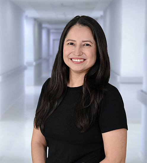 Es la foto de perfil de una nefróloga en Ciudad Juárez de Hospital Angeles Ciudad Juárez. Usa una bata blanca, blusa blanca con lunares rojos y cabello largo, tiene arracadas.