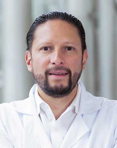 Es la foto de perfil de un ginecólogo y obstetra en Huixquilucan de Hospital Angeles Lomas. Tiene bata blanca con camisa blanca, tiene barba de candado.