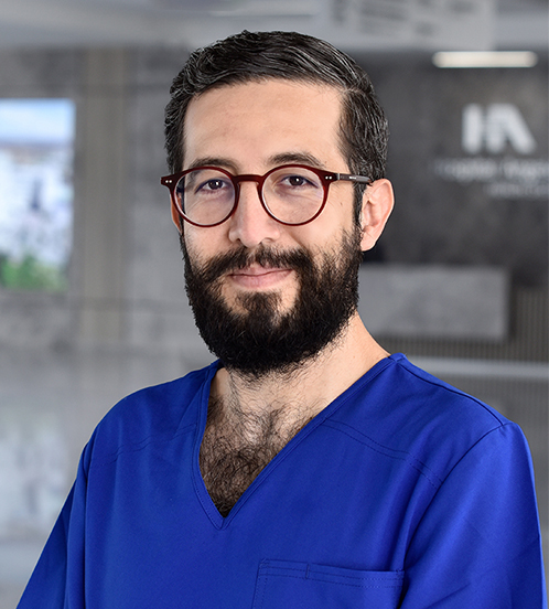 Es la foto de perfil de un gastroenterólogo en Querétaro de Hospital Angeles Centro Sur. Tiene barba y lentes, y usa un uniforme azul.