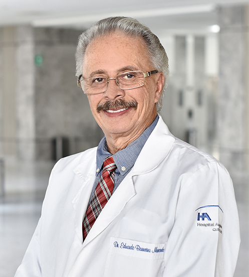 Es la foto de perfil de un reumatólogo en Querétaro de Hospital Angeles Centro Sur. Usa una bata blanca, camisa azul y corbata roja con rayas blancas y negras. Tiene bigote y lentes.