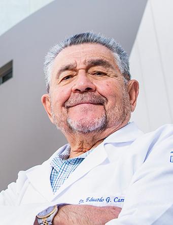 Es la foto de perfil de un ortopedista y traumatólogo en Huixquilucan de Hospital Angeles Lomas. Usa una bata blanca con camisa, tiene los brazos cruzados y el cabello canoso.