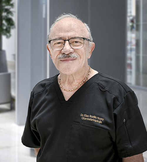Es la foto de perfil de un otorrinolaringólogo en Huixquilucan de Hospital Angeles Lomas. Usa un chaleco azul marino, con camisa azul cielo, tiene corbata, y usa lentes.