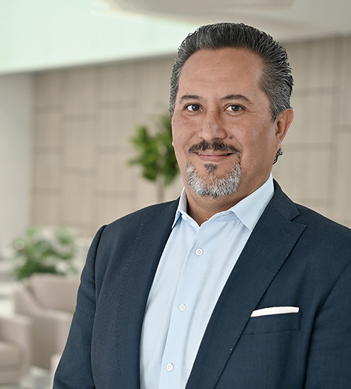 Es la foto de perfil de un ginecólogo y obstetra en Querétaro de Hospital Angeles Centro Sur. Usa un traje azul marino y una camisa azul cielo, tiene barba y cabello canoso.