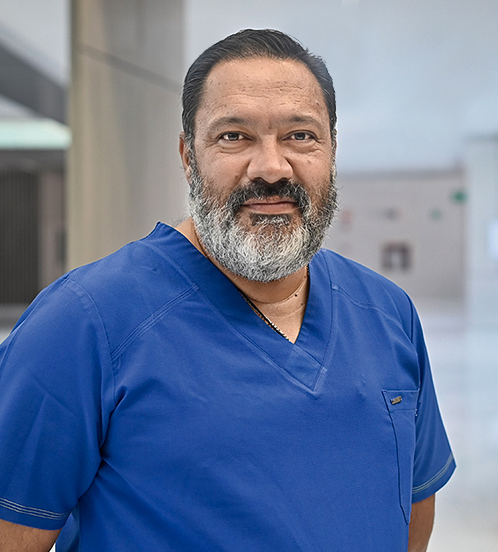 Es la foto de perfil de un cirujano neurológico pediátrico en Querétaro de Hospital Angeles Centro Sur. Usa un uniforme azul, tiene barba y bigote.