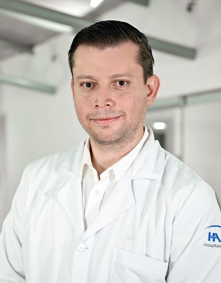 Es la foto de perfil de un ortopedista y traumatólogo en Ciudad de México de Hospital Angeles Santa Mónica. Usa una bata y camisa blanca. Tiene el cabello negro.