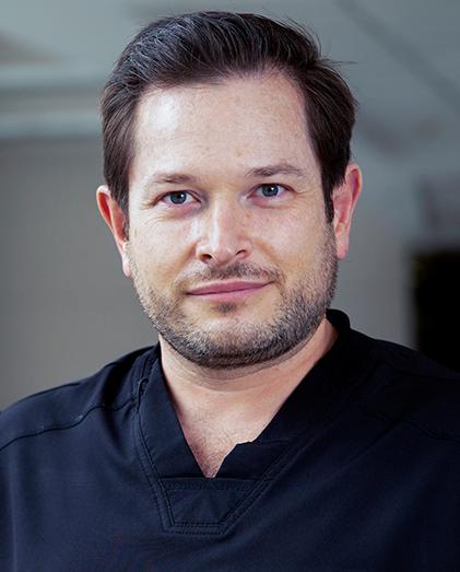 Es la foto de perfil de un otorrinolaringólogo en Huixquilucan de Hospital Angeles Lomas. Usa un uniforme negro, está sonriendo, es de tez blanca y cabello oscuro.
