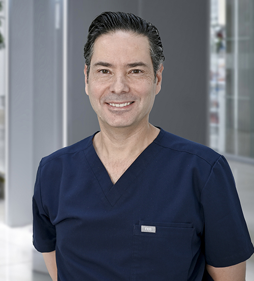 Es la foto de perfil de un cirujano general especialista en cirugía oncológica en Huixquilucan de Hospital Angeles Lomas. Tiene una corbata azul rey, camisa y una bata. 