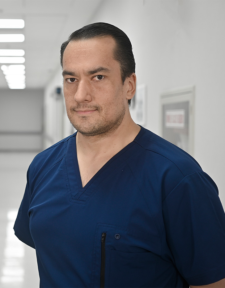 Es la foto de perfil de un internista, inmunólogo y alergólogo en Ciudad de México de Hospital Angeles Universidad. Usa un uniforme médico color azul. Tiene el cabello negro y los brazos cruzados por detrás.