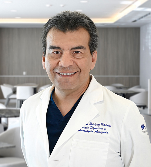 Es la foto de perfil de un cirujano general en San Pedro Garza de Hospital Angeles Valle Oriente. Usa un saco color negro y una camis azul claro. Tiene el cabello negro y está sonriendo.