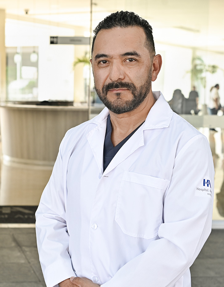 Es la foto de perfil de un otorrinolaringólogo en Ciudad de México de Hospital Angeles. El doctor tiene una bata blanca y una corbata azul marino con detalles en color blanco.
