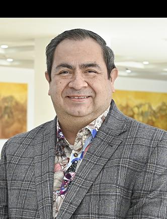 Es la foto de perfil de un ginecólogo y obstetra especialista en biología de reproducción en Ciudad Juárez de Hospital Angeles Ciudad Juárez. El doctor viste un saco gris con cuadros y una camisa colorida. 