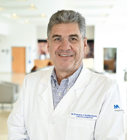 Es la foto de perfil de un cirujano general en Xalapa de Hospital Angeles Xalapa. Usa un uniforme médico azul. Tiene el cabello negro y está sobriendo.