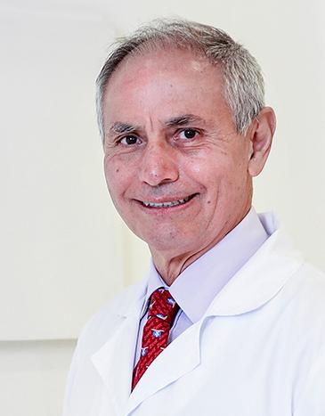 Es la foto de perfil de un otorrinolaringólogo especialista en audiología y foniatría en León de Hospital Angeles León. Usa una bata blanca con una camisa lila y una corbata roja. 