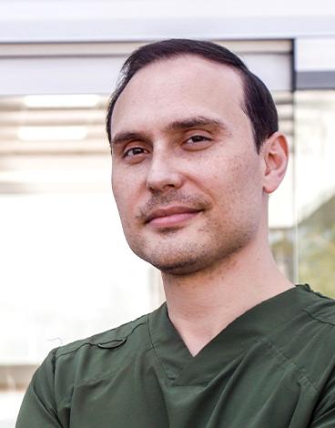 Es la foto de perfil de un oftalmólogo en Guadalajara de Hospital Angeles Del Carmen. Tiene un uniforme médico verde olivo. está sonriendo suavemente.