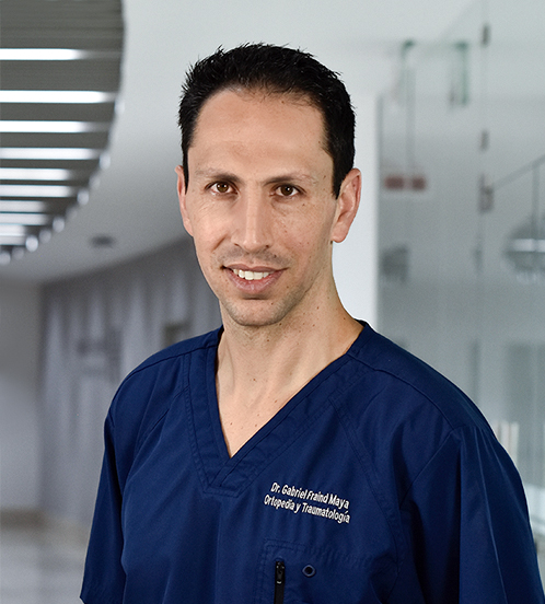 Es la foto de perfil de un ortopedista y traumatólogo en Huixquilucan de Hospital Angeles Lomas. Tiene un uniforme azul marino con cuello V. Es de tez morena y está sonriendo.