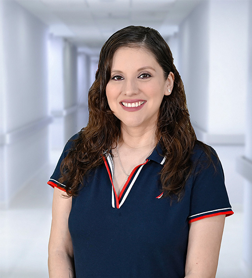 Es la foto de perfil de una cardióloga en Ciudad Juárez de Hospital Angeles Ciudad Juárez. Viste una bata blanca con una blusa verde, es de tez blanca y tiene labial rojo.